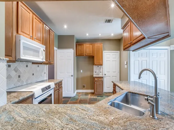 a kitchen with a refrigerator sink and wooden cabinets