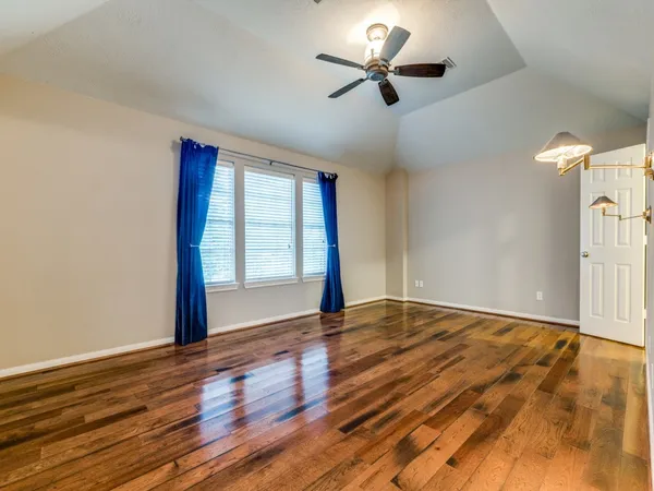 a view of an empty room with a window and wooden floor