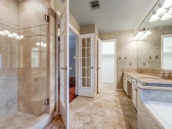 a spacious bathroom with a granite countertop sink a mirror and a shower