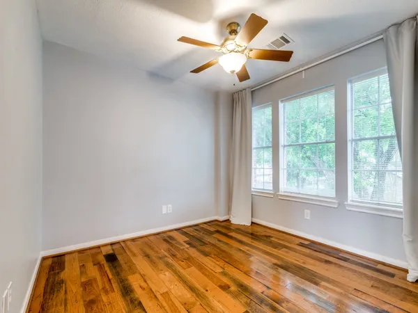 a view of a bedroom with wooden floor and a ceiling fan