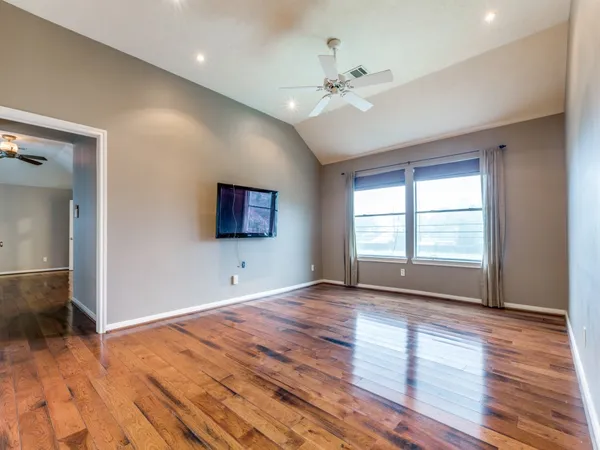 a view of an empty room with wooden floor and a window