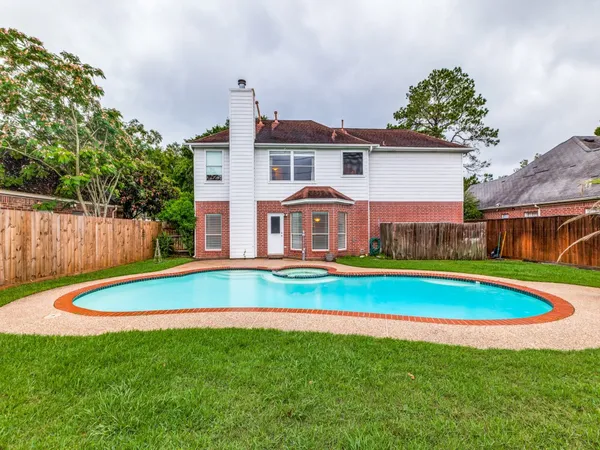 a view of pool with umbrella and trees in the background
