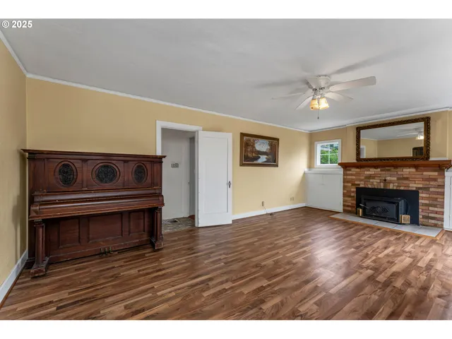 a view of an empty room with wooden floor fireplace and a window