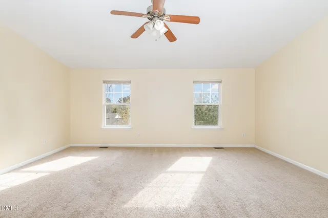 an empty room with a ceiling fan and a window