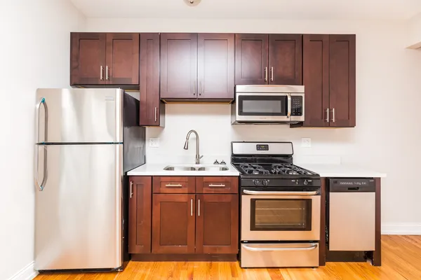 a kitchen with stainless steel appliances granite countertop wooden cabinets a stove a microwave and a refrigerator