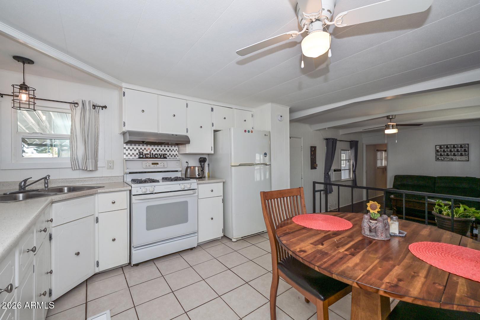 16225 North Cave Creek Road, Unit 79 Phoenix, AZ 85032 - Photo 4 of 32 a kitchen with stainless steel appliances granite countertop a dining table chairs and white cabinets