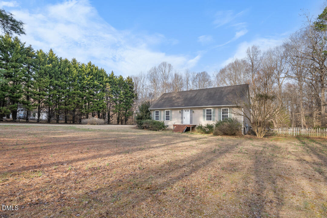 a view of a house with a yard and large trees