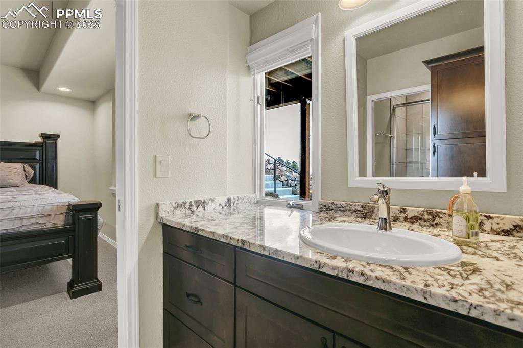 14525 Sterling Road Colorado Springs, CO 80921 - Photo 28 of 46 a en suite bathroom with a granite countertop sink and a mirror