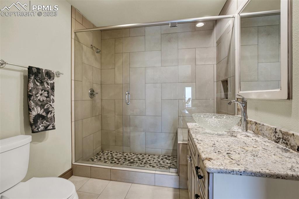 14525 Sterling Road Colorado Springs, CO 80921 - Photo 32 of 46 a bathroom with a granite countertop sink a mirror and a shower