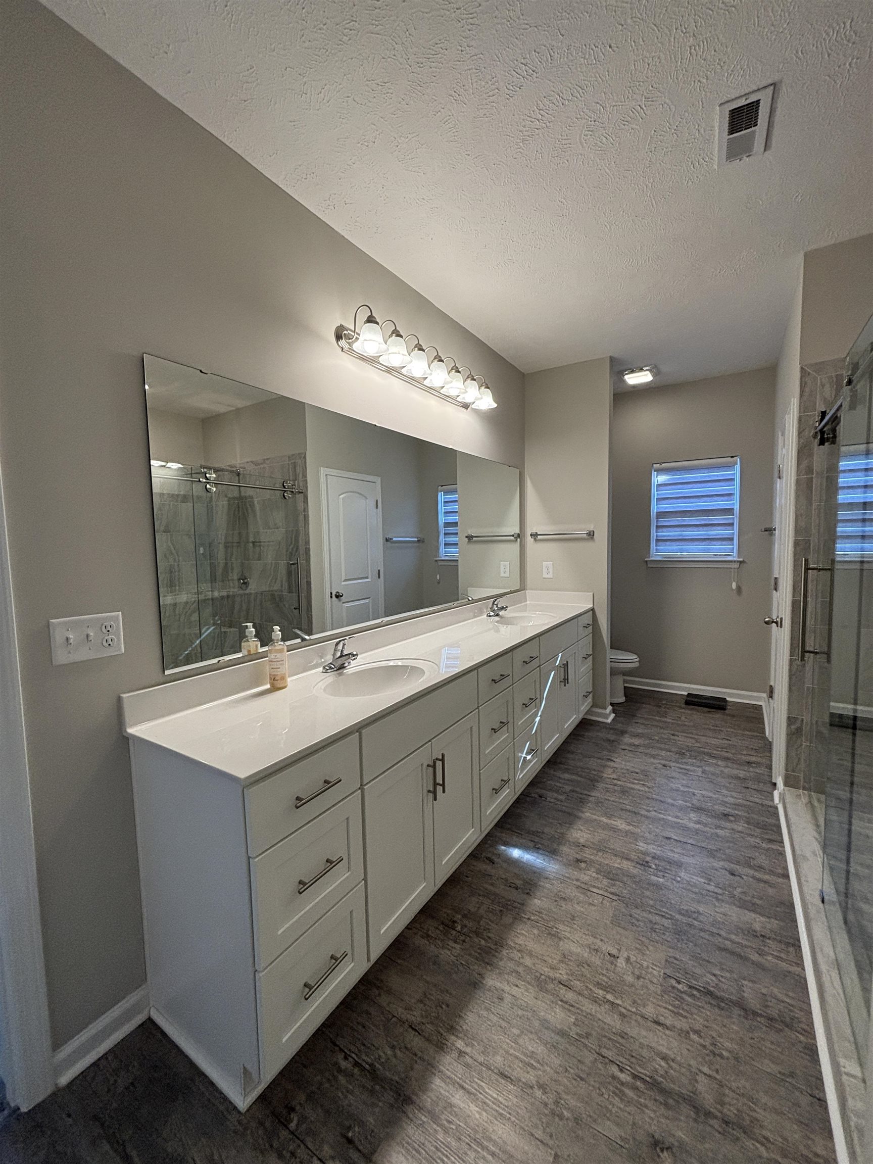 227 Leste Road Myrtle Beach, SC 29588 - Photo 11 of 33 Full bath featuring double vanity, a stall shower, a textured ceiling, and dark wood-style flooring