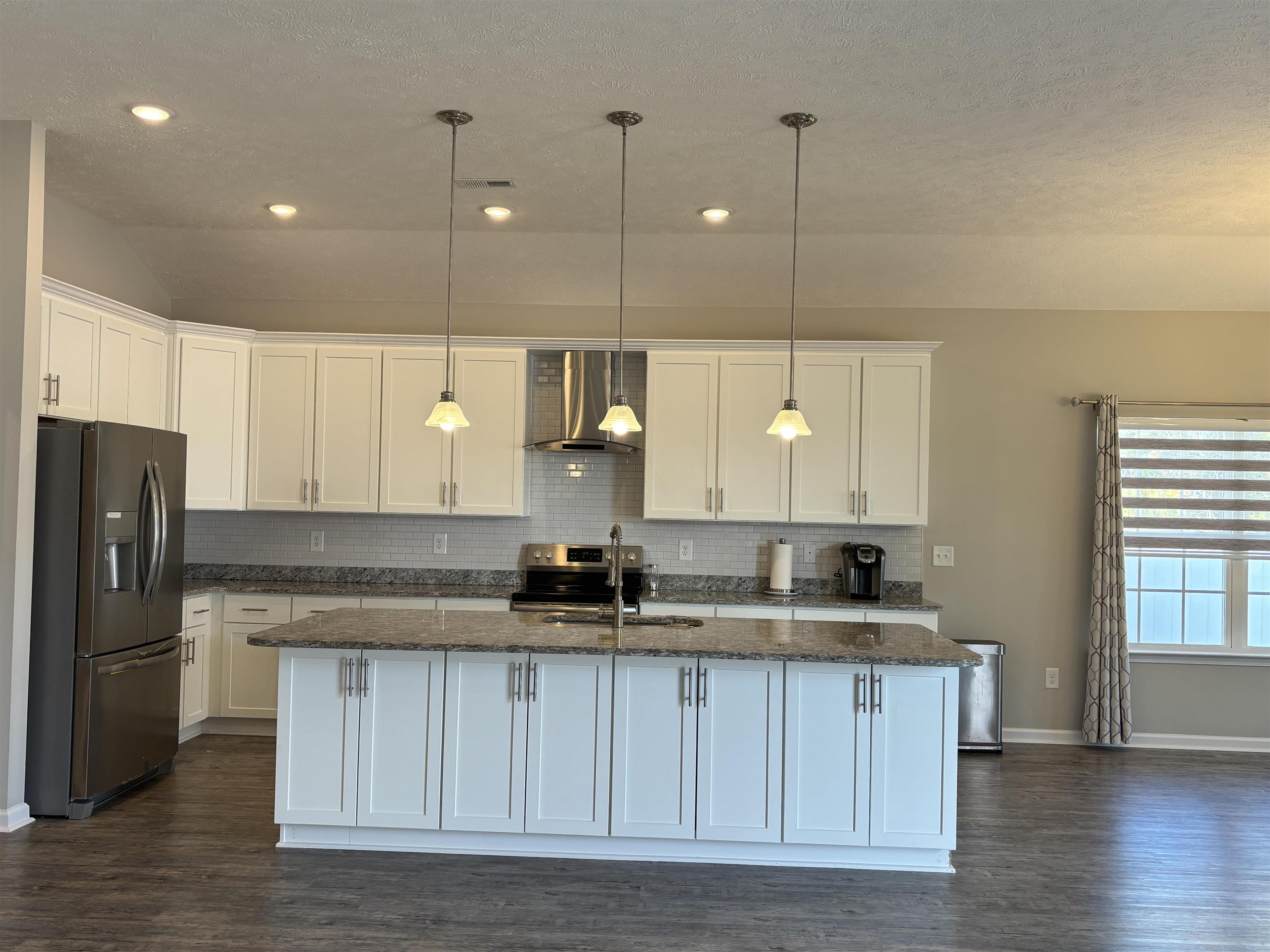 227 Leste Road Myrtle Beach, SC 29588 - Photo 4 of 33 Kitchen featuring stainless steel appliances, dark stone countertops, wall chimney range hood, white cabinets, and an island with sink