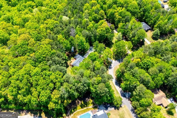 an aerial view of residential house with outdoor space and trees all around