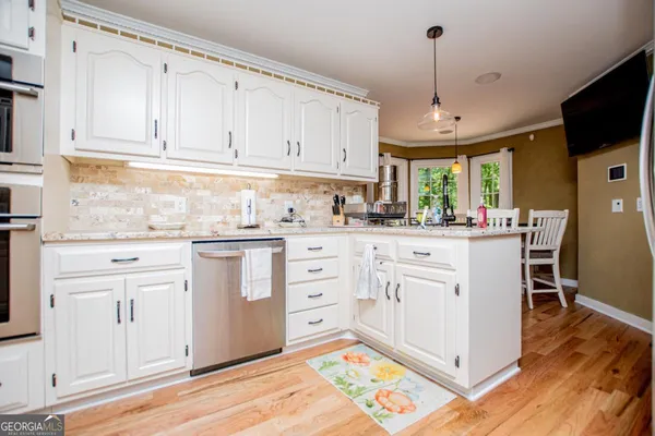 a kitchen with stainless steel appliances kitchen island granite countertop a table chairs and a wooden floor