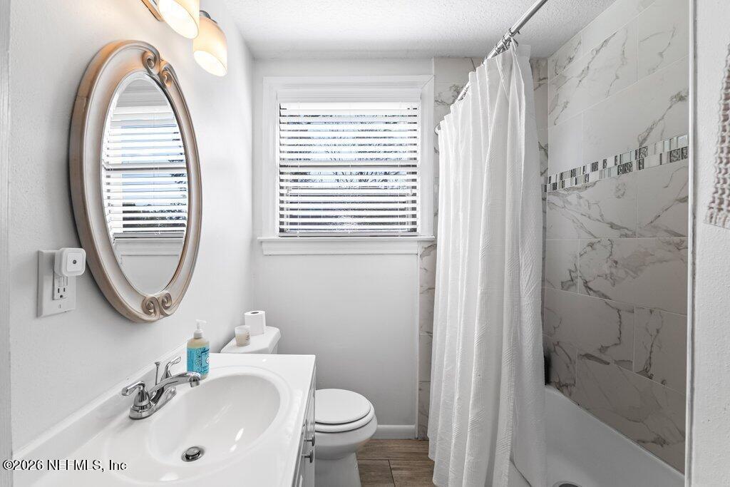 4145 Springwood Road Jacksonville, FL 32207 - Photo 20 of 33 a bathroom with a sink a mirror a toilet and a window