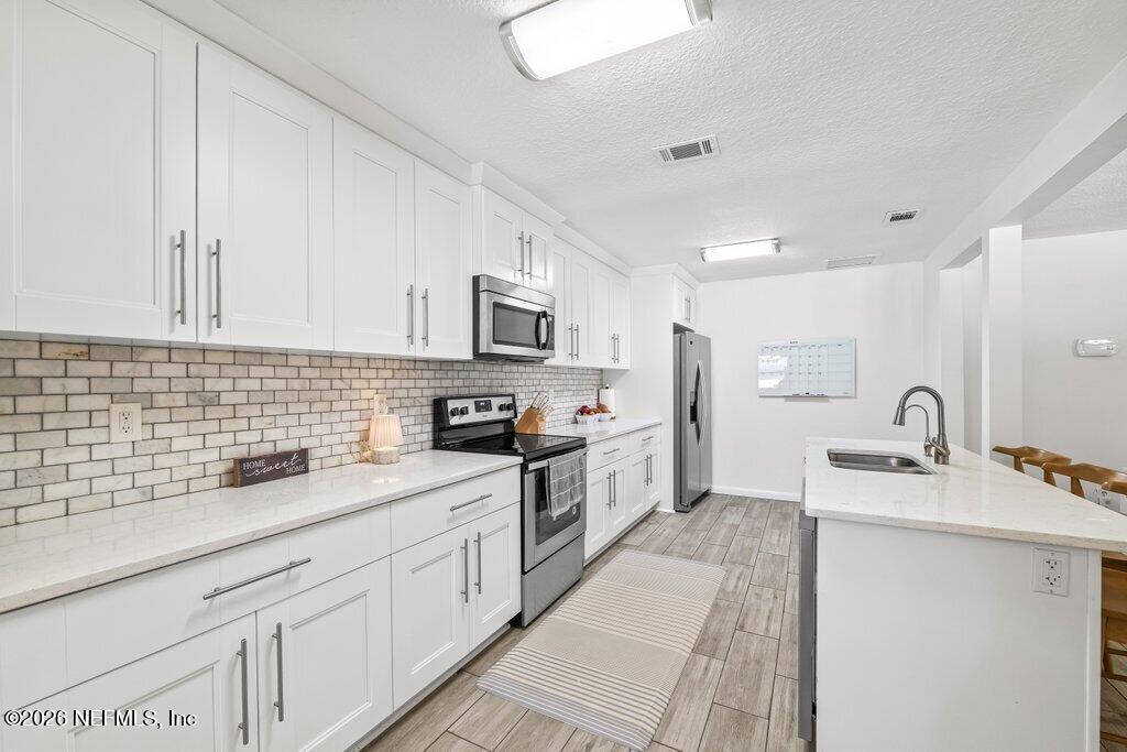 4145 Springwood Road Jacksonville, FL 32207 - Photo 2 of 33 a kitchen with stainless steel appliances kitchen island granite countertop a sink dishwasher stove and white cabinets