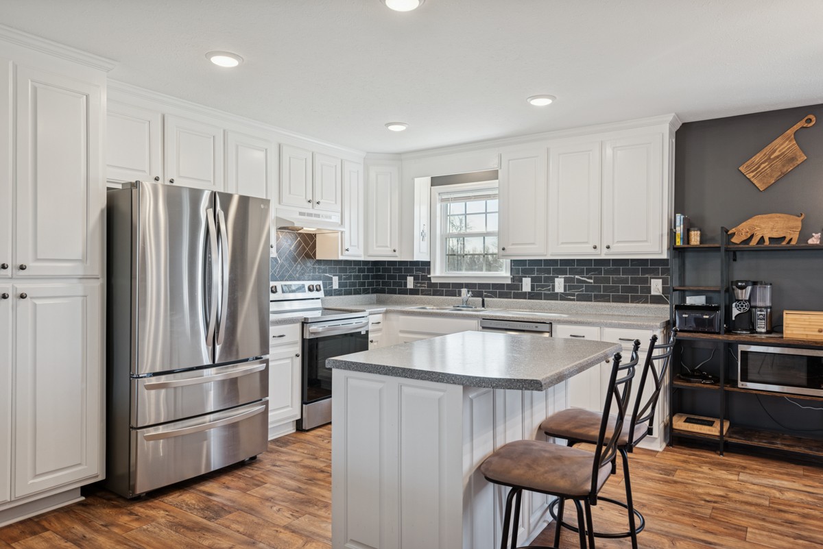 4915 Little Dry Creek Road Pulaski, TN 38478 - Photo 12 of 45 a kitchen with granite countertop a refrigerator stove and wooden floor