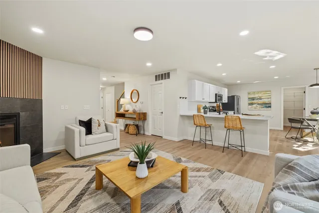 a living room with furniture kitchen view and a wooden floor