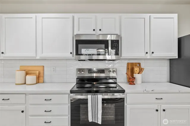 a kitchen with granite countertop white cabinets and white appliances