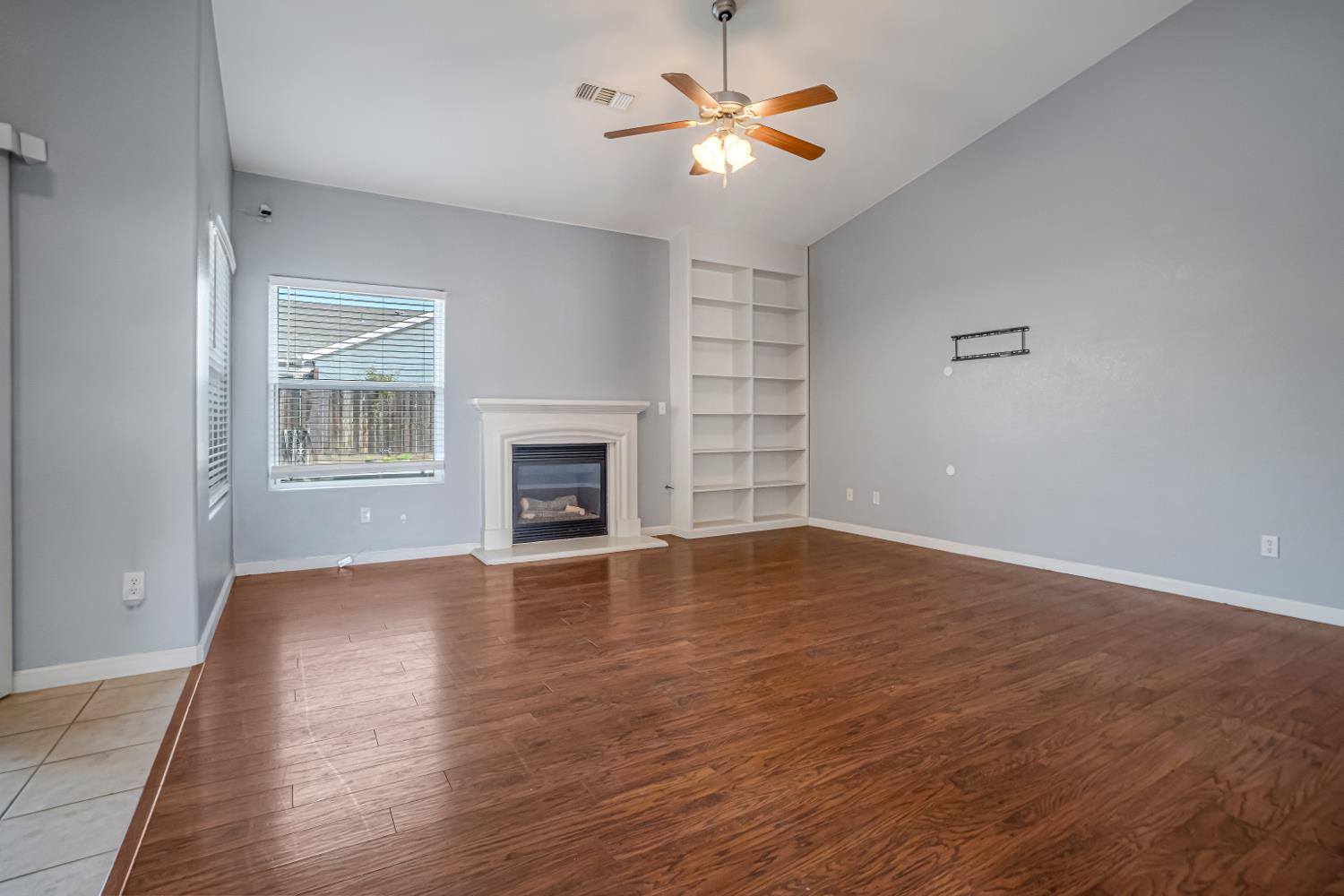 3062 North Filbert Avenue Fresno, CA 93727 - Photo 6 of 41 an empty room with wooden floor fireplace and windows