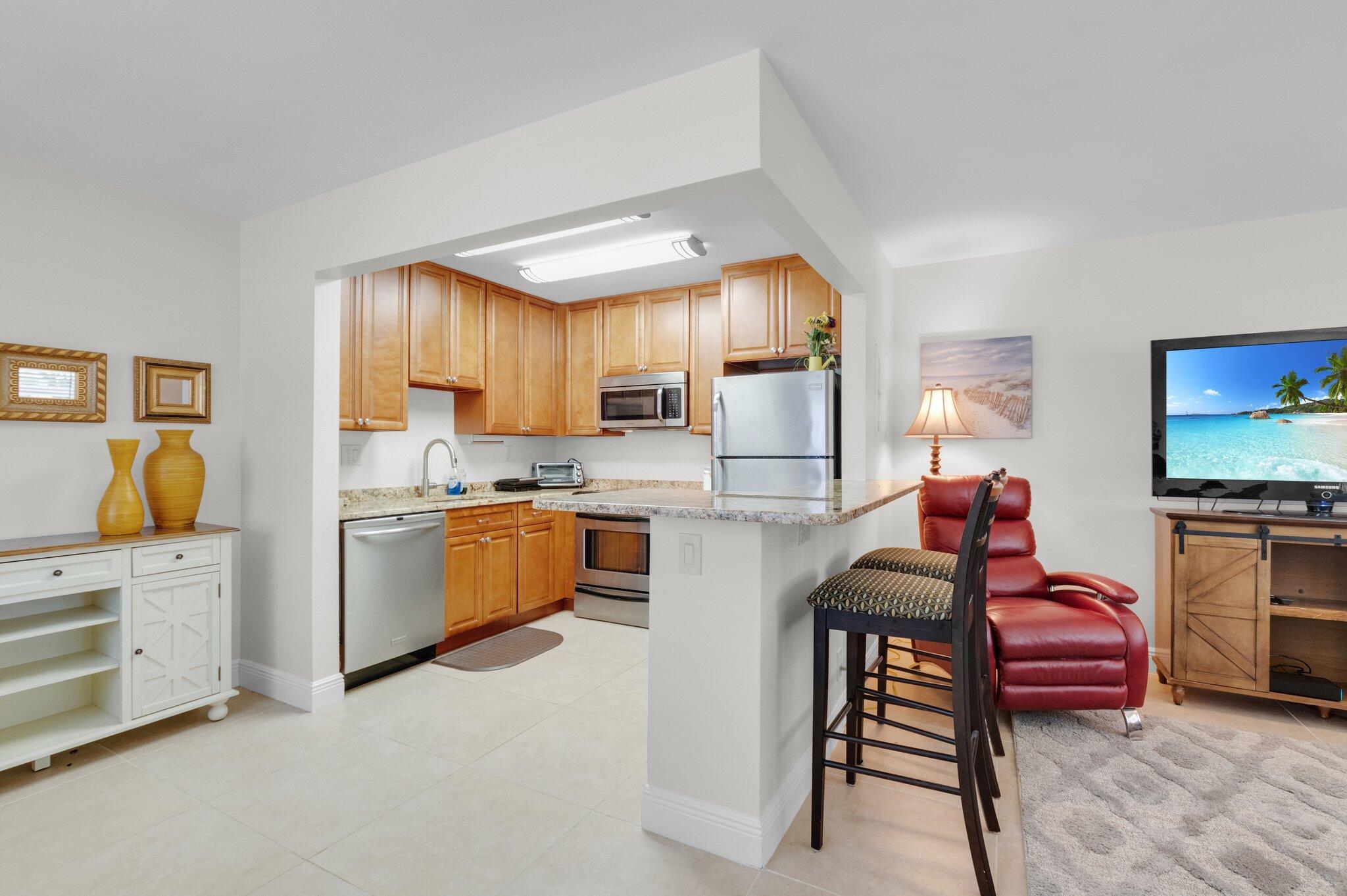 392 Monaco Way, Unit 392 Delray Beach, FL 33446 - Photo 14 of 47 a kitchen with white cabinets and stainless steel appliances
