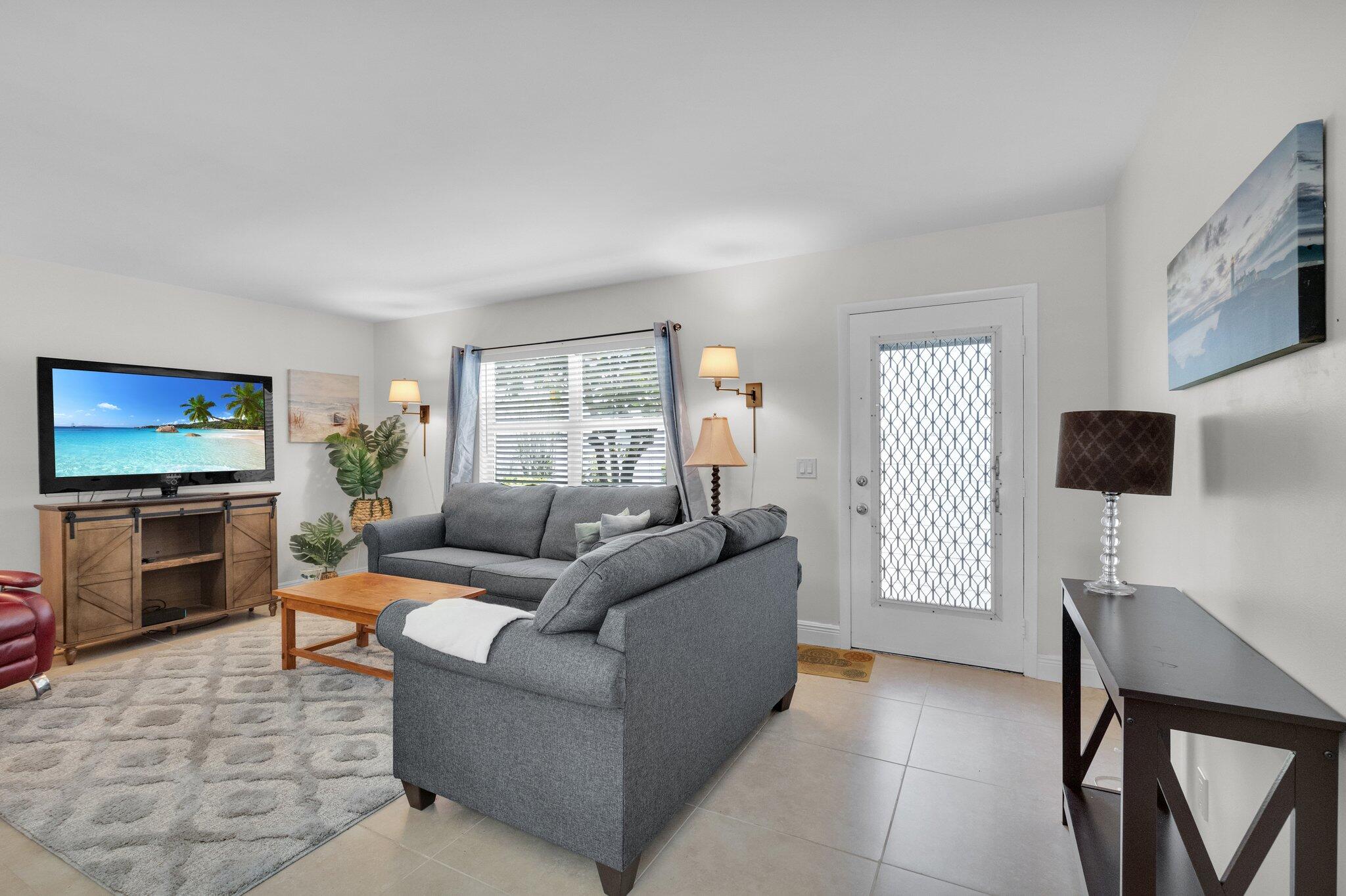 392 Monaco Way, Unit 392 Delray Beach, FL 33446 - Photo 7 of 47 a living room with furniture a flat screen tv and a window