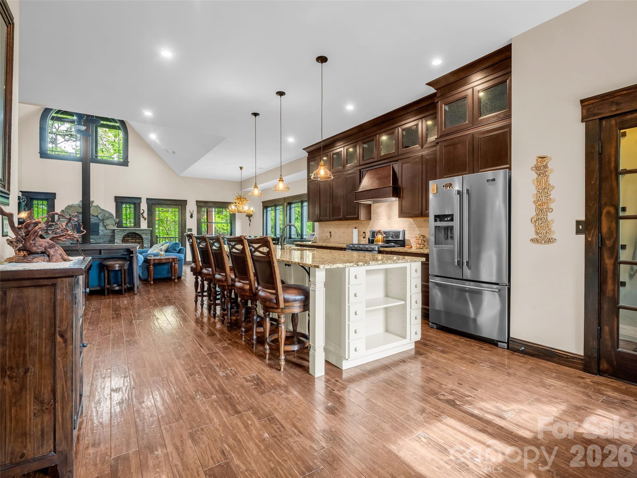 174 Rock Ridge Lake Lure, NC 28746 - Photo 7 of 48 a kitchen with stainless steel appliances kitchen island granite countertop a refrigerator oven a sink a dining table and chairs with wooden floor