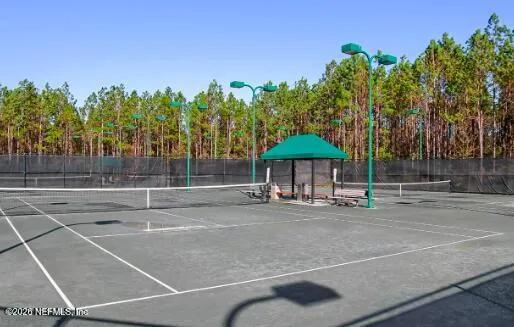 a view of a tennis ground with trees in front of it