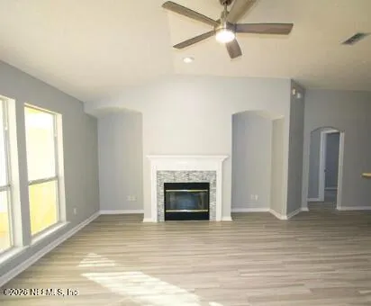 a view of an empty room with wooden floor fireplace and a window