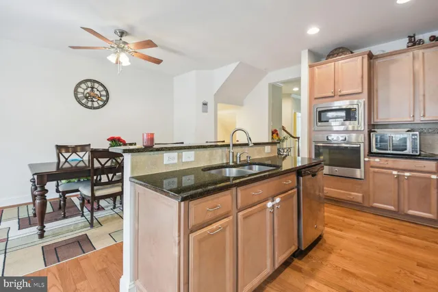 a kitchen with stainless steel appliances granite countertop a sink cabinets and wooden floor