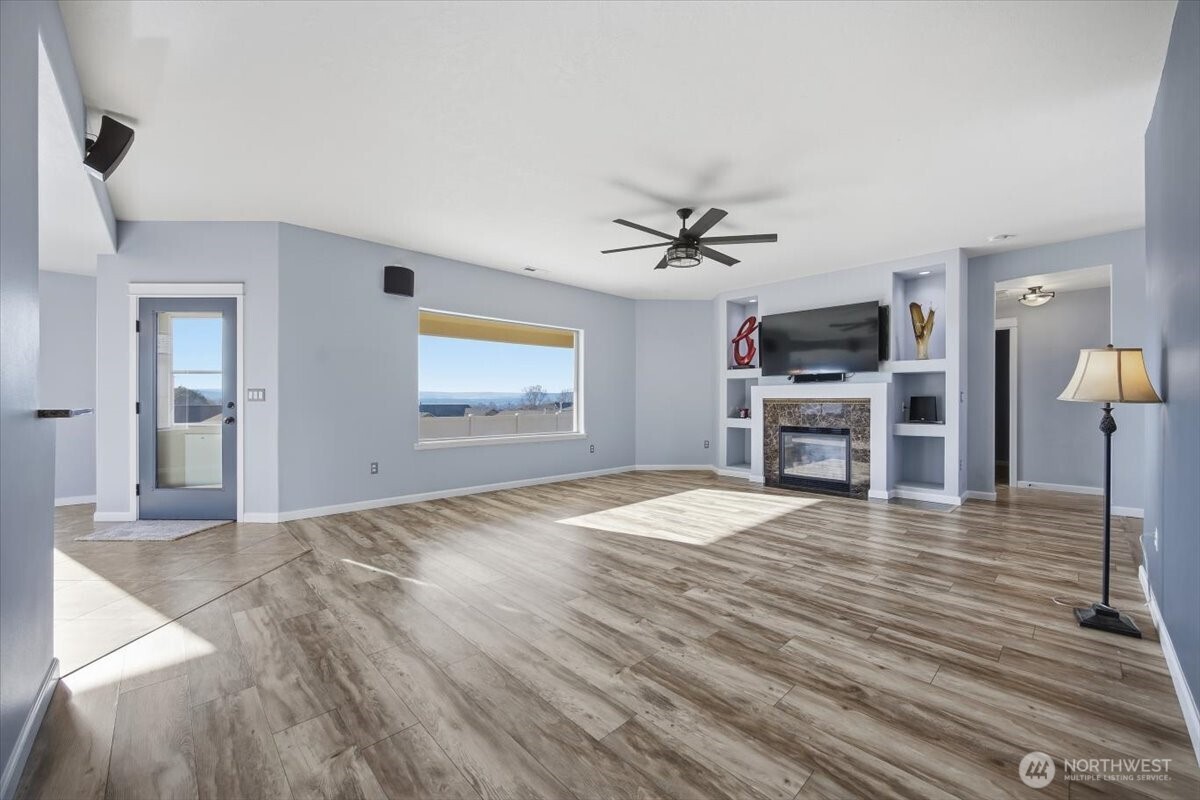 6304 Turf Paradise Drive Pasco, WA 99301 - Photo 19 of 40 a view of a livingroom with a flat screen tv wooden floor and a ceiling fan