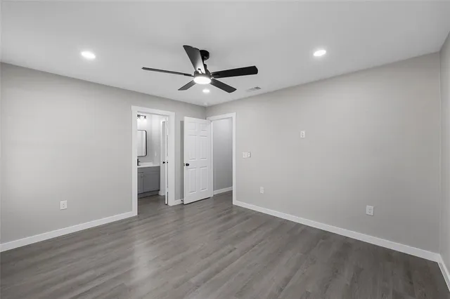 a view of an empty room with wooden floor and a ceiling fan