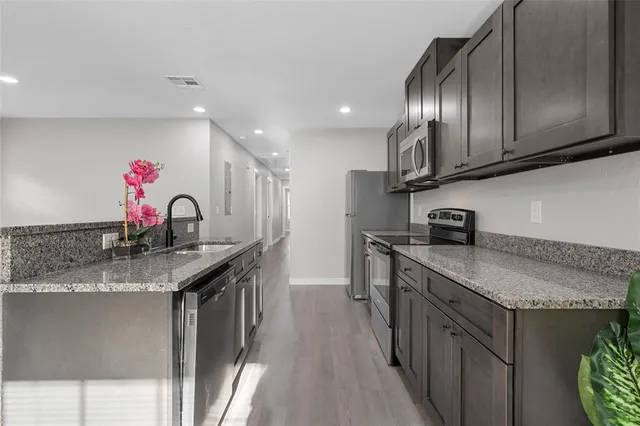 a kitchen with stainless steel appliances granite countertop a sink stove and cabinets