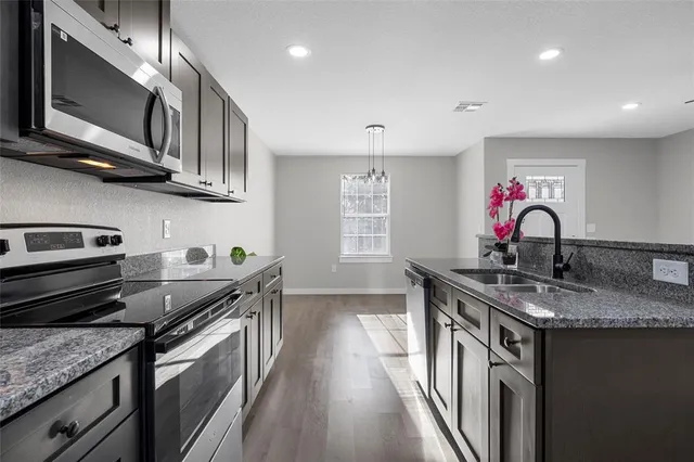 a kitchen with stainless steel appliances granite countertop a sink stove and cabinets
