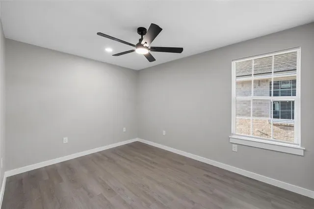 an empty room with wooden floor fan and windows