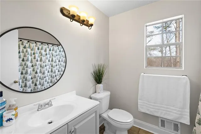 a bathroom with a sink a mirror a toilet and a window