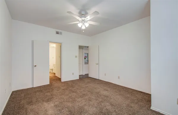 a view of an empty room with chandelier fan
