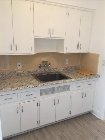 a kitchen with granite countertop white cabinets and a sink