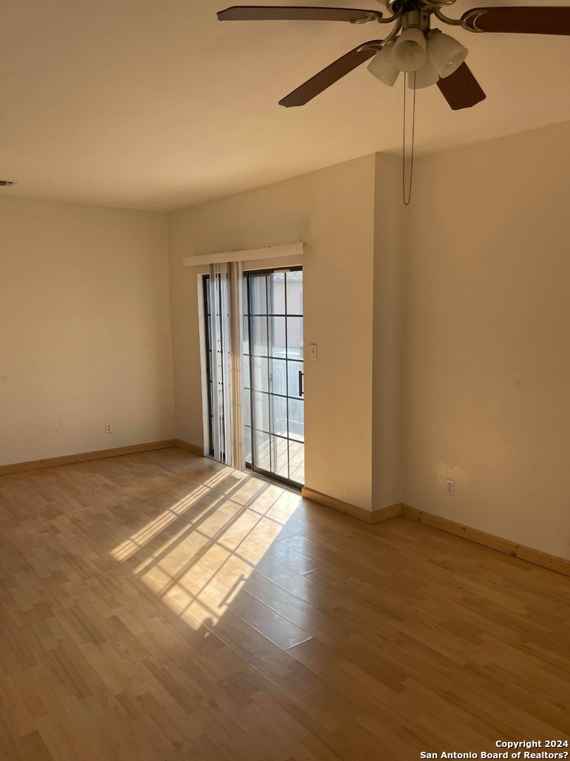 an empty room with wooden floor fan and windows
