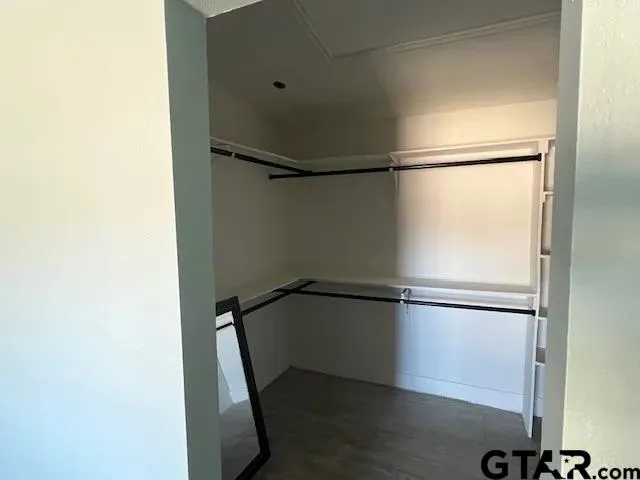 a walk in closet with wooden floor