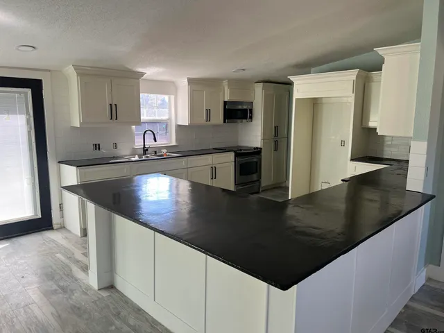 a kitchen with stainless steel appliances granite countertop a sink a stove counter space and cabinets