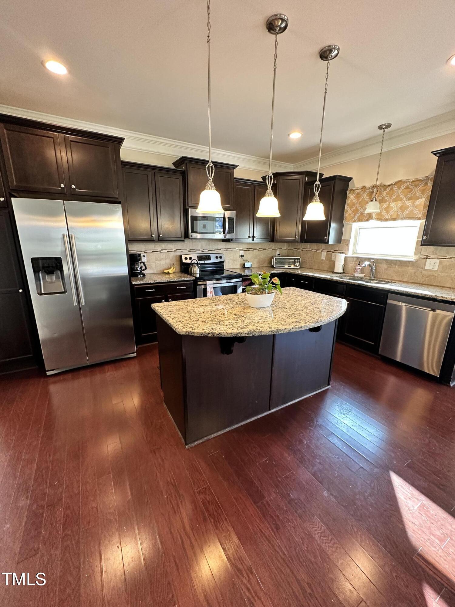 8305 Pin Cherry Drive Willow Spring, NC 27592 - Photo 22 of 60 a large kitchen with stainless steel appliances granite countertop a sink a stove and a wooden floors