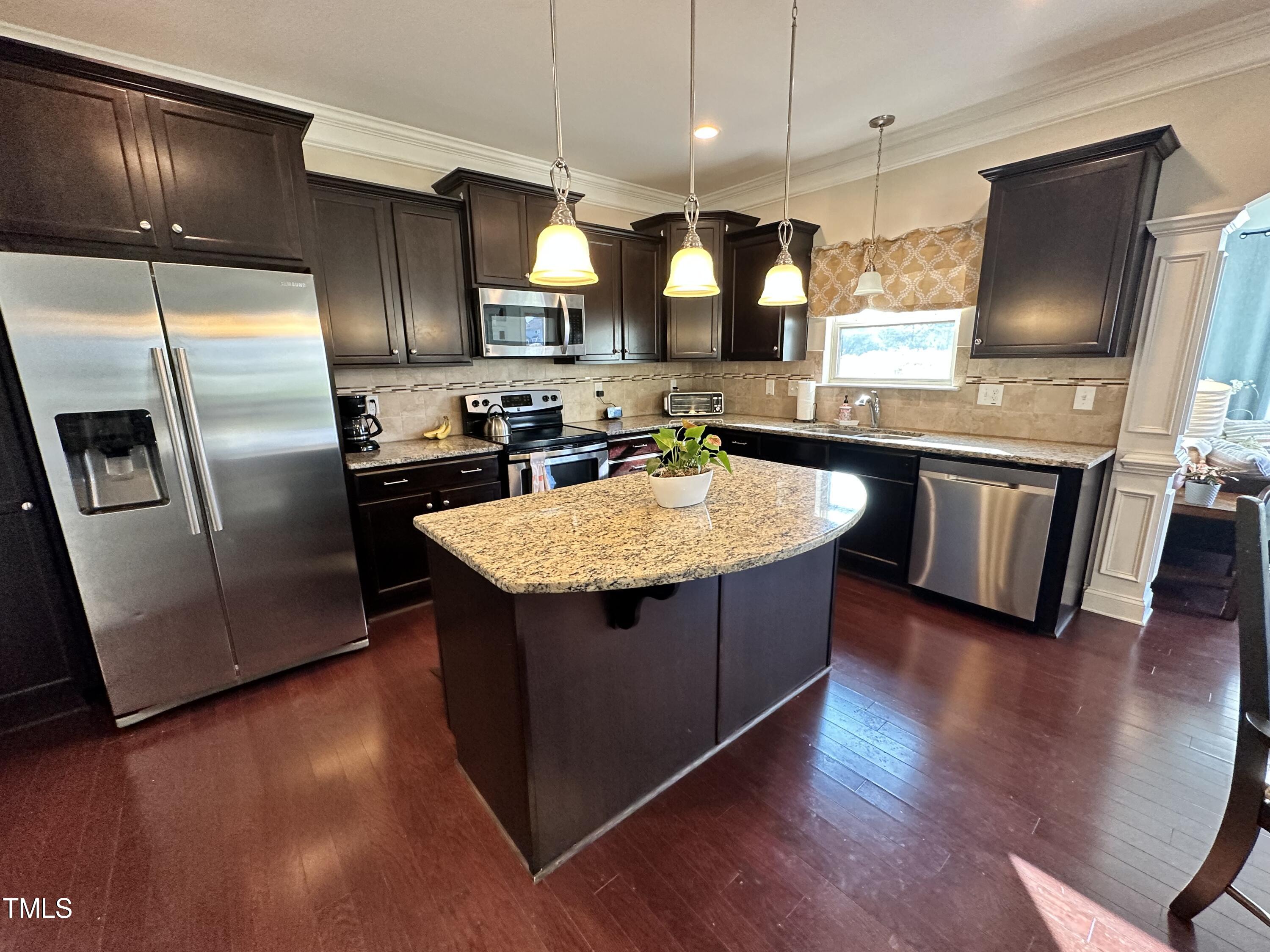 8305 Pin Cherry Drive Willow Spring, NC 27592 - Photo 23 of 60 a kitchen with stainless steel appliances granite countertop a refrigerator a sink a stove and wooden floors