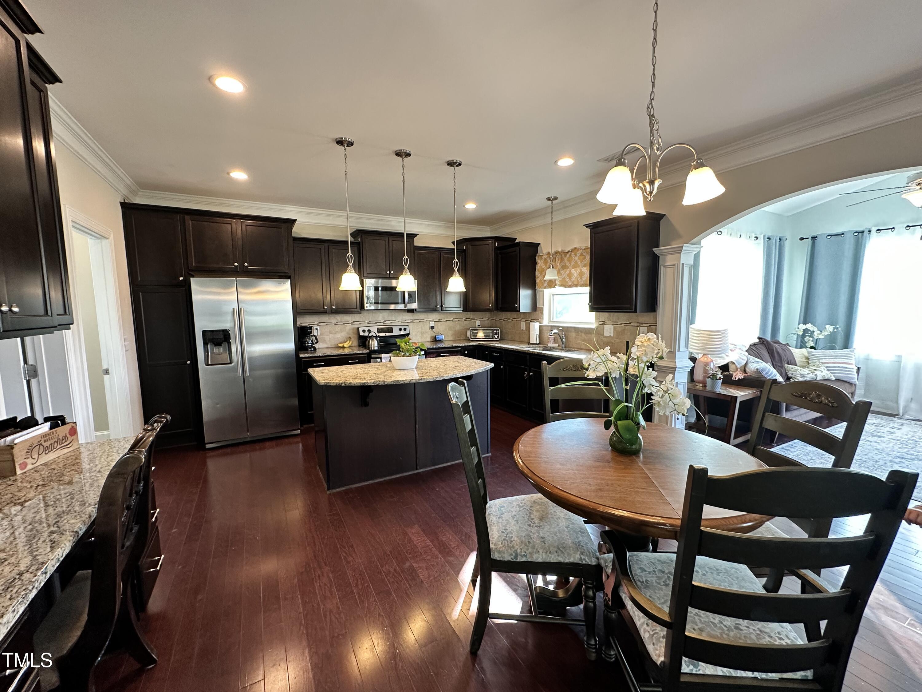 8305 Pin Cherry Drive Willow Spring, NC 27592 - Photo 24 of 60 a kitchen with stainless steel appliances kitchen island granite countertop a sink a stove a dining table and chairs