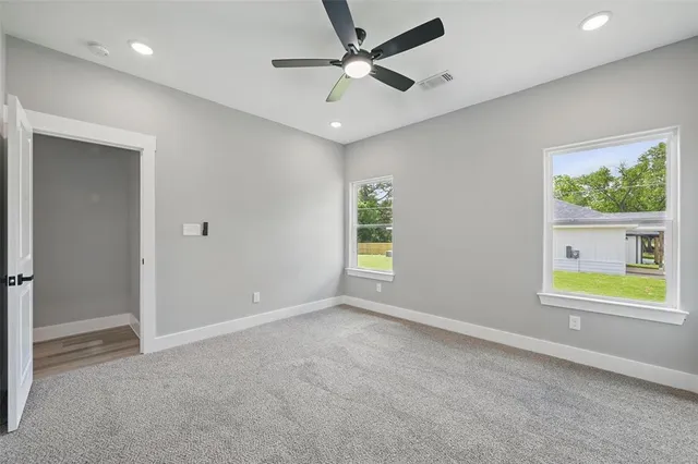 an empty room with windows and a ceiling fan