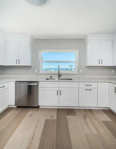 a kitchen with granite countertop a refrigerator cabinets and wooden floor