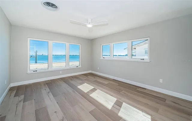 a view of an empty room with a window and wooden floor