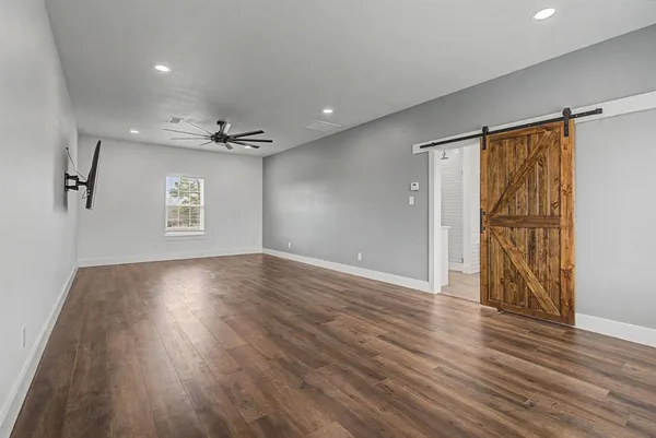 a view of an empty room with wooden floor and a window