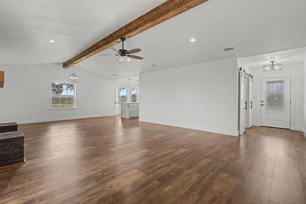 an empty room with wooden floor chandelier and windows