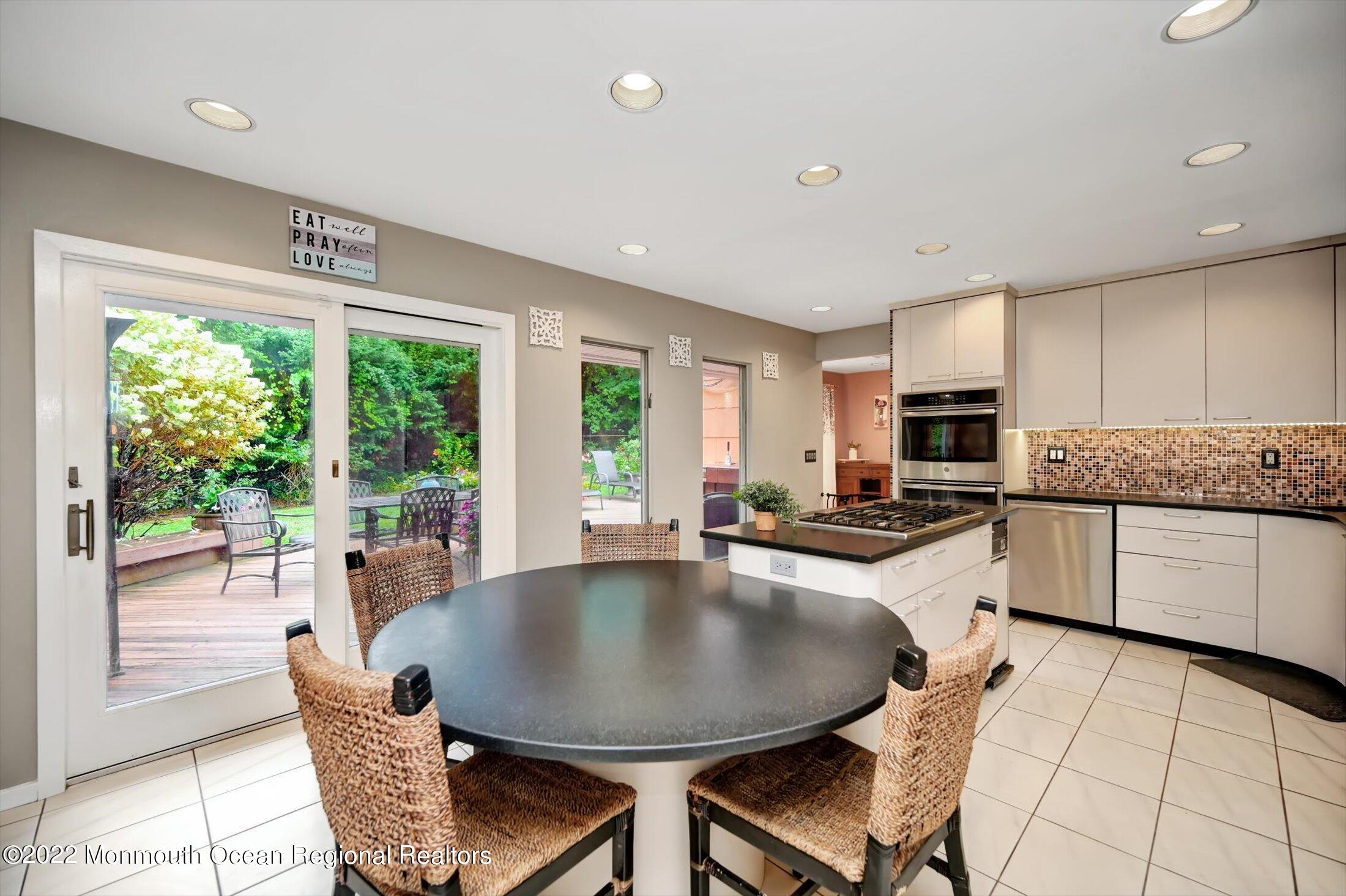 a kitchen with stainless steel appliances granite countertop a stove a table and chairs in it