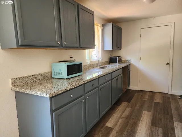a kitchen with granite countertop a sink a stove and cabinets